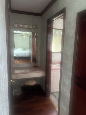 A bedroom with a bed, a vanity with a mirror, a ceiling fan, and a small stool. - 5 Star Home Cut Off, private, peaceful, comfortable, Enjoy sunsets by the pool. (Cut Off)