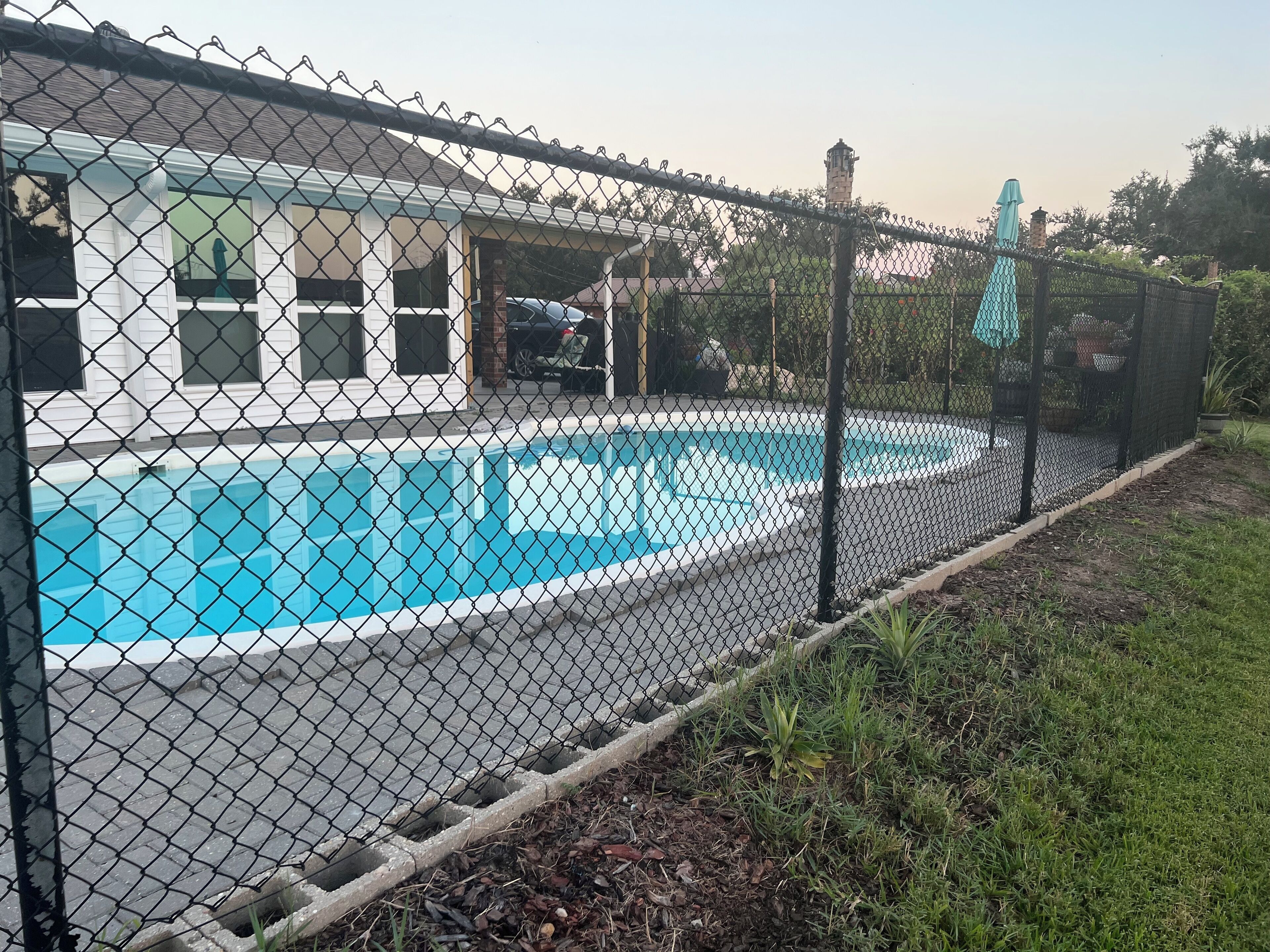 A fenced swimming pool area with a house in the background.