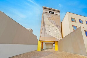 Een modern gebouw met een unieke gevel, een bord waarop 'Townhouse' staat en een verhard entreegebied.