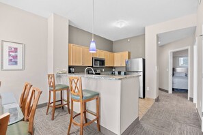 A modern kitchen with wooden cabinets, a central island, and bar stools.