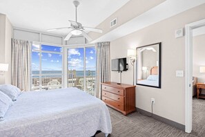 Una camera d'albergo con un letto, una televisione, una cassettiera, uno specchio e vista sulla città.