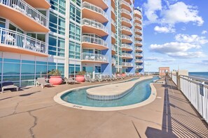 A pool area with lounge chairs and a view of the ocean.