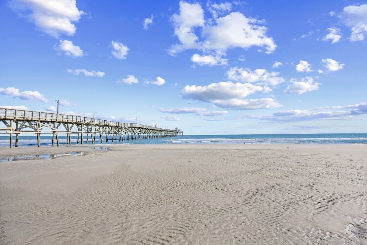 A beach with a pier extending into the ocean.