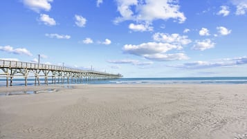 A beach with a pier extending into the ocean.