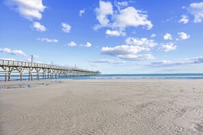 Ein Strand mit einem Steg, der sich ins Meer erstreckt.