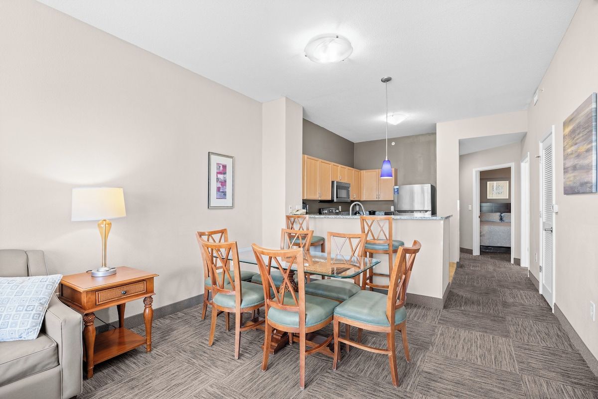 A compact living space with a dining area, kitchenette, and a small bedroom.