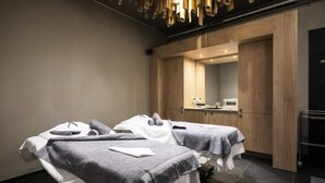 Ein moderner Spa-Raum mit zwei Behandlungsliegen, Holzschränken und einem großen Spiegel.