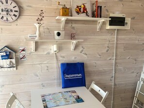 A room with a wooden wall, a clock, a map on the table, and a blue bag with text. - 6 Person Holiday Home in Svanesund (Svanesund)