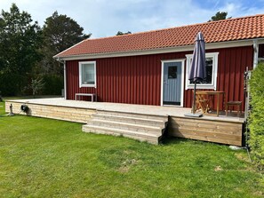 A red wooden house with a red-tiled roof, a front door, and a small porch with steps leading to the entrance. - 6 Person Holiday Home in Svanesund (Svanesund)