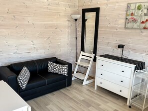 A room with a black leather sofa, a white dresser, a floor lamp, and a mirror on the wall. - 6 Person Holiday Home in Svanesund (Svanesund)