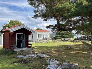 Une maison à deux étages, dotée d’une structure surmontée d’un toit rouge et d’un bâtiment blanc avec de grandes fenêtres.