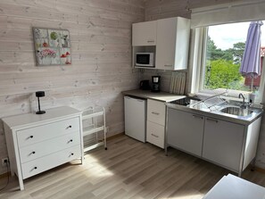A compact kitchen with white cabinets, a microwave, a coffee maker, and a sink. - 6 Person Holiday Home in Svanesund (Svanesund)