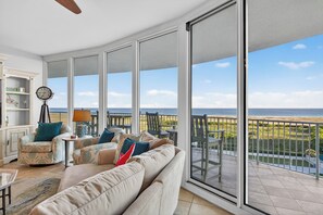 A spacious balcony with a view of the beach, a sofa with patterned cushions, and a clock on a tripod stand. - NEW TO RENTAL! Professionally decorated and STUNNING 3 bedroom unit!! (Orange Beach)