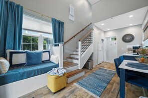 Un intérieur moderne comprenant un escalier, un coin repas et un espace détente avec un canapé et des coussins.