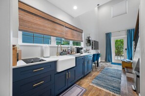 Une cuisine moderne avec des meubles de couleur bleu foncé, un îlot central et une vue sur l’extérieur.