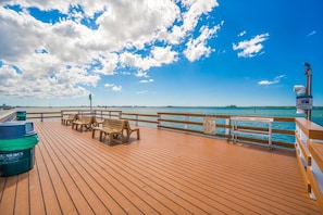Une terrasse en bois, dotée de bancs et d’une poubelle, qui offre une vue sur une étendue d’eau sous un ciel dégagé.