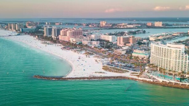 Zona turística costera con playa, hoteles de gran altura y un puerto deportivo.