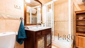 A bathroom with a marble sink, wooden cabinet, and a large mirror. - Apartment two steps away from Plaza Mayor (Madrid)