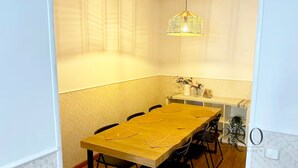 A dining area with a wooden table, black chairs, a hanging light fixture, and a small plant on the counter. - Apartment two steps away from Plaza Mayor (Madrid)