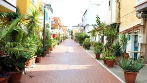 A narrow brick pathway lined with potted plants and buildings on both sides. - Casa Chica (Málaga)