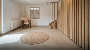 Un intérieur moderne avec un escalier en bois, un tapis rond tissé et un mur miroir.