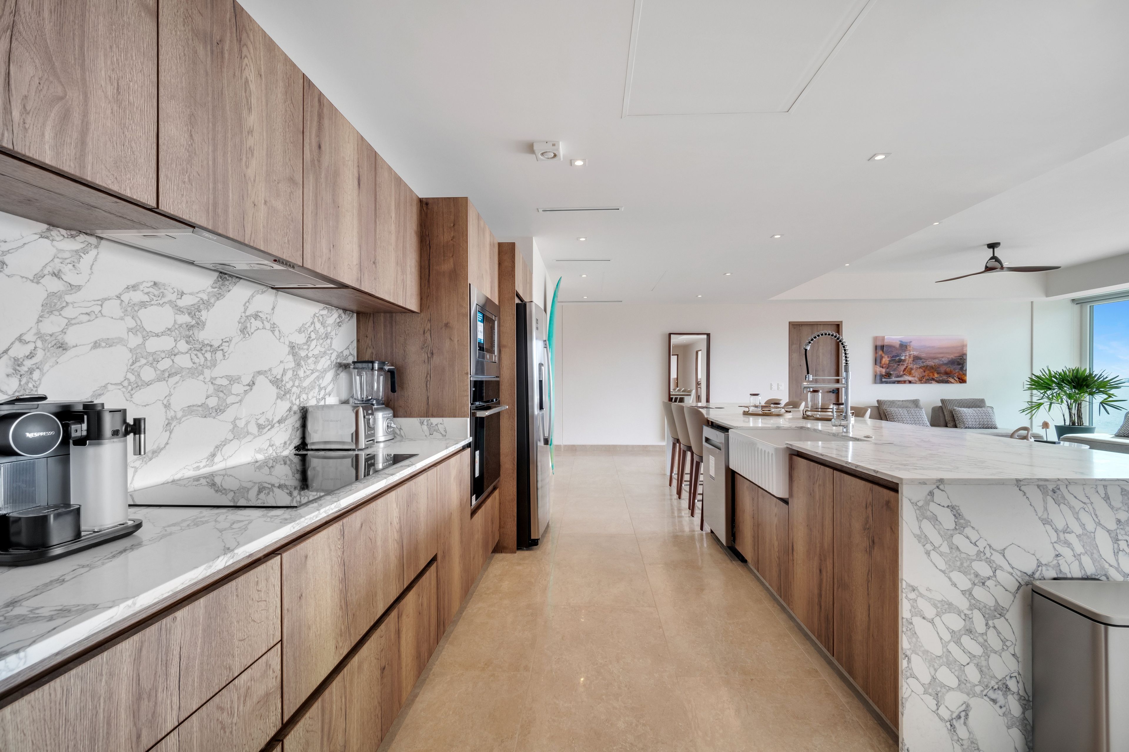 A modern kitchen with marble countertops, wooden cabinets, and a central island.