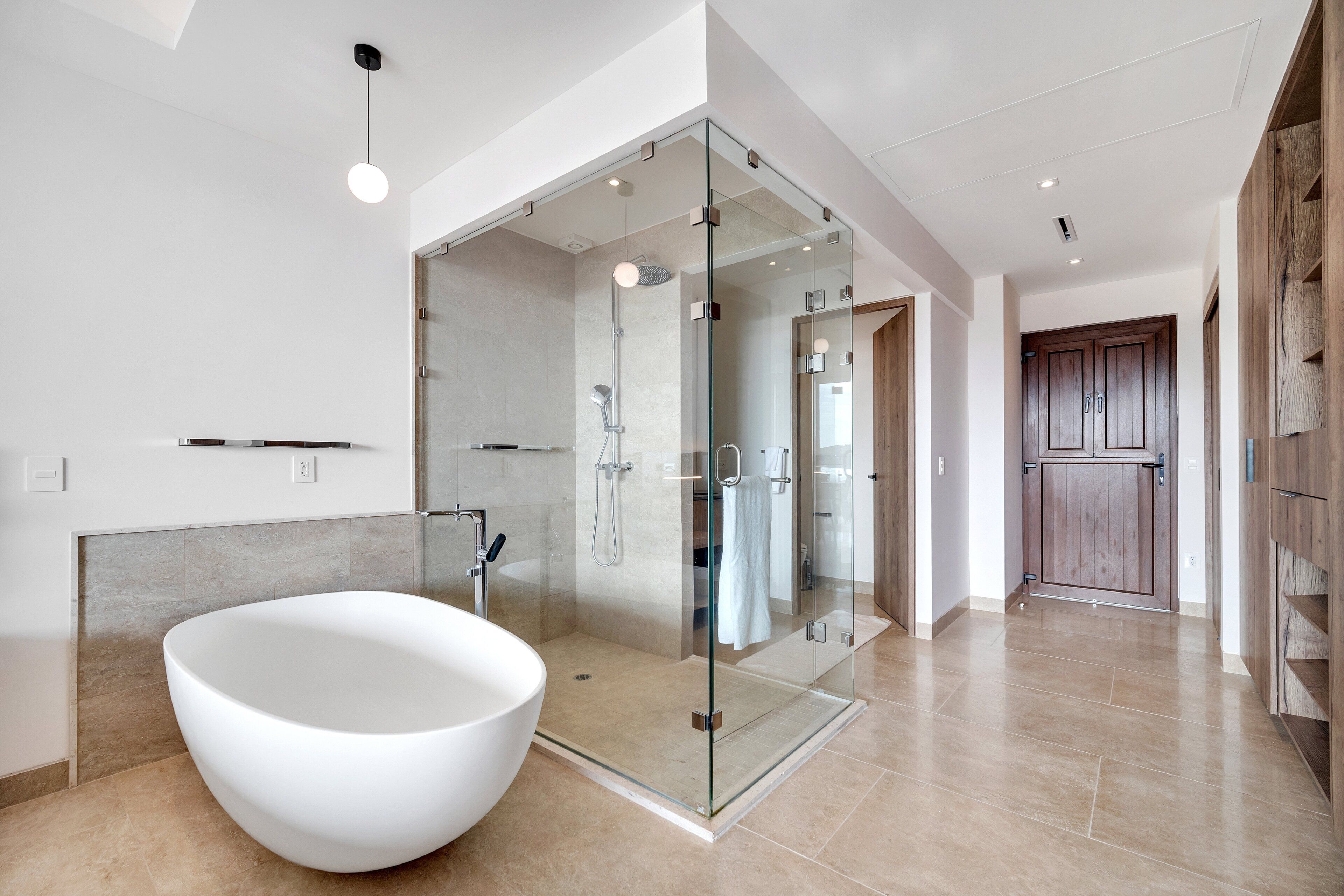 Une salle de bain moderne avec une baignoire sur pieds, une douche à parois de verre et une porte en bois.