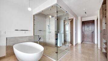 Une salle de bain moderne avec une baignoire sur pieds, une douche à parois de verre et une porte en bois.