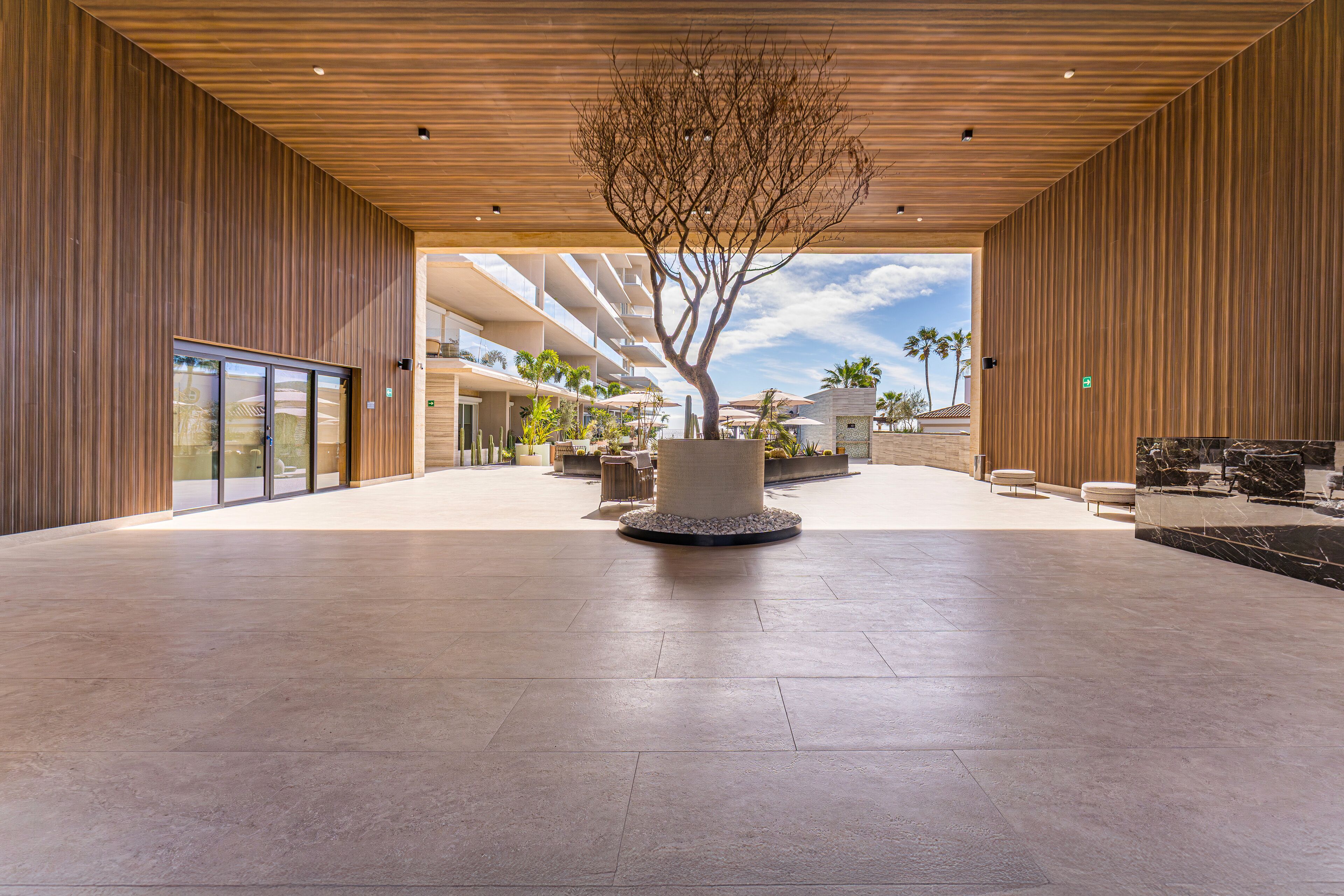 Un amplio vestíbulo con un árbol central, arquitectura moderna y vistas de los edificios circundantes.