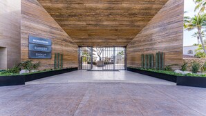 A modern building entrance with a wooden ceiling and a tiled floor. There are three signs on the wall: "MODUVATED," "SURENO," and "SANJO." - Albaluz (San Jose del Cabo)