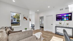 A modern living room with a grey sofa, a TV mounted on the wall, and a wooden floor. - Elgin Escape –Near Train, Parks & Restaurants (Elgin)