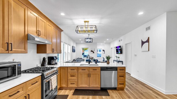 A modern kitchen with wooden cabinets, stainless steel appliances, and a central island. - Elgin Escape –Near Train, Parks & Restaurants (Elgin)