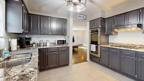 A modern kitchen with dark cabinets, a stainless steel sink, a microwave, and a double oven.