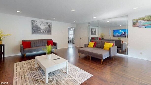 A spacious living room with two sofas, a coffee table, and a large mirror reflecting the room.