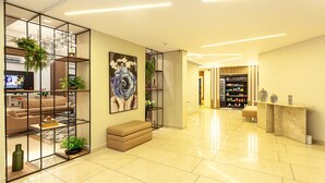 A modern hotel lobby with a seating area, a reception desk, and a visible store in the background. - Executive apartment on Paulista Avenue – across from Rosewood and Soho House SP (São Paulo)