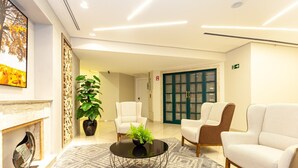 A lobby with a fireplace, a round black coffee table with a plant, two armchairs, and a patterned rug. - Executive apartment on Paulista Avenue – across from Rosewood and Soho House SP (São Paulo)