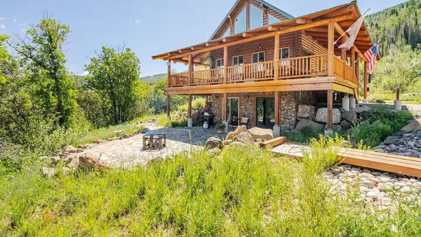 A wooden cabin with a balcony, stone foundation, and a fire pit in the yard. - Lower Cozy Cabin in Powderhorn Ski Resort (Mesa)