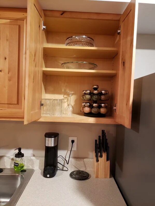 A kitchen with wooden cabinets, a coffee maker, a soap dispenser, and a knife block.