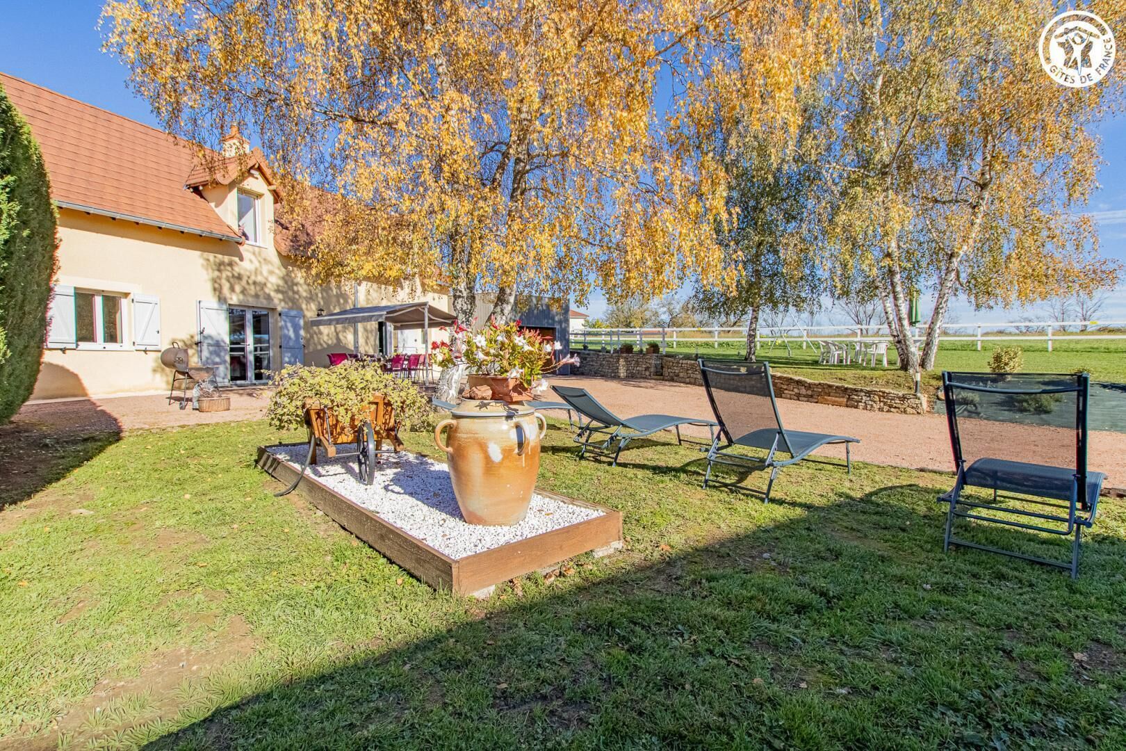 A house with a patio area, outdoor seating, and a large decorative pot.