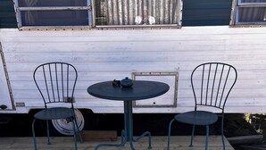 Una terraza de madera con una mesa redonda y dos sillas.