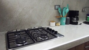 Eine Küche mit einem Gasherd, einer Kaffeemaschine und Küchenutensilien auf der Arbeitsfläche.