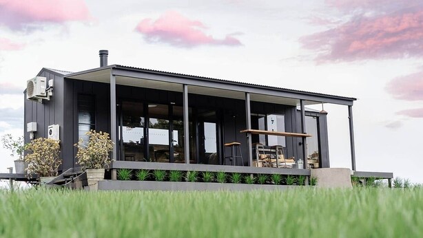 A modern house with large windows, a covered porch, and a flat roof.