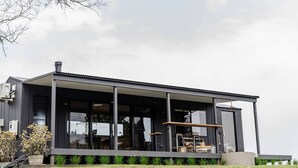 A modern house with a large glass front and a covered outdoor area.