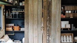Een landelijke keuken met houten kasten, een hanglamp en planken vol keukengerei.
