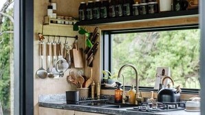 A compact kitchen with wooden cabinets, a black countertop, and various utensils and appliances.