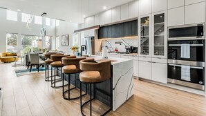 A modern kitchen with a central island, bar stools, and built-in appliances. - Luxury Newly Built 4 BR 4 Bath Home w/ Rooftop and Grill! (Dallas)