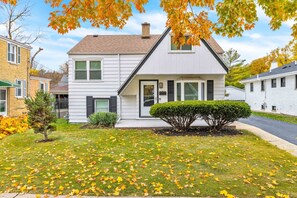 A two-story house with a front porch, a small front yard, and a tree with autumn leaves. - Bright & Cozy Elmhurst Stay • 3BR/2BA (Elmhurst)