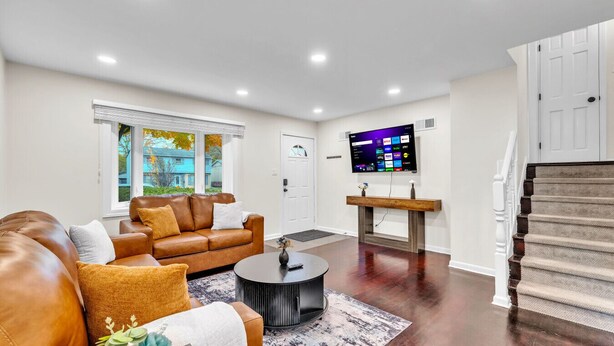 Un salon moderne avec un canapé en cuir, une table basse et un téléviseur à écran plat fixé au mur.