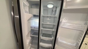 Een keuken met een inbouwkoelkast, een magnetron en een spoelbak.