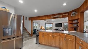 A modern kitchen with wooden cabinets, a stainless steel refrigerator, and a built-in island. - 3946 - Summers by the Sea - Duck OBX Retreat w/ Pool & Hot Tub Near Beach (Duck)